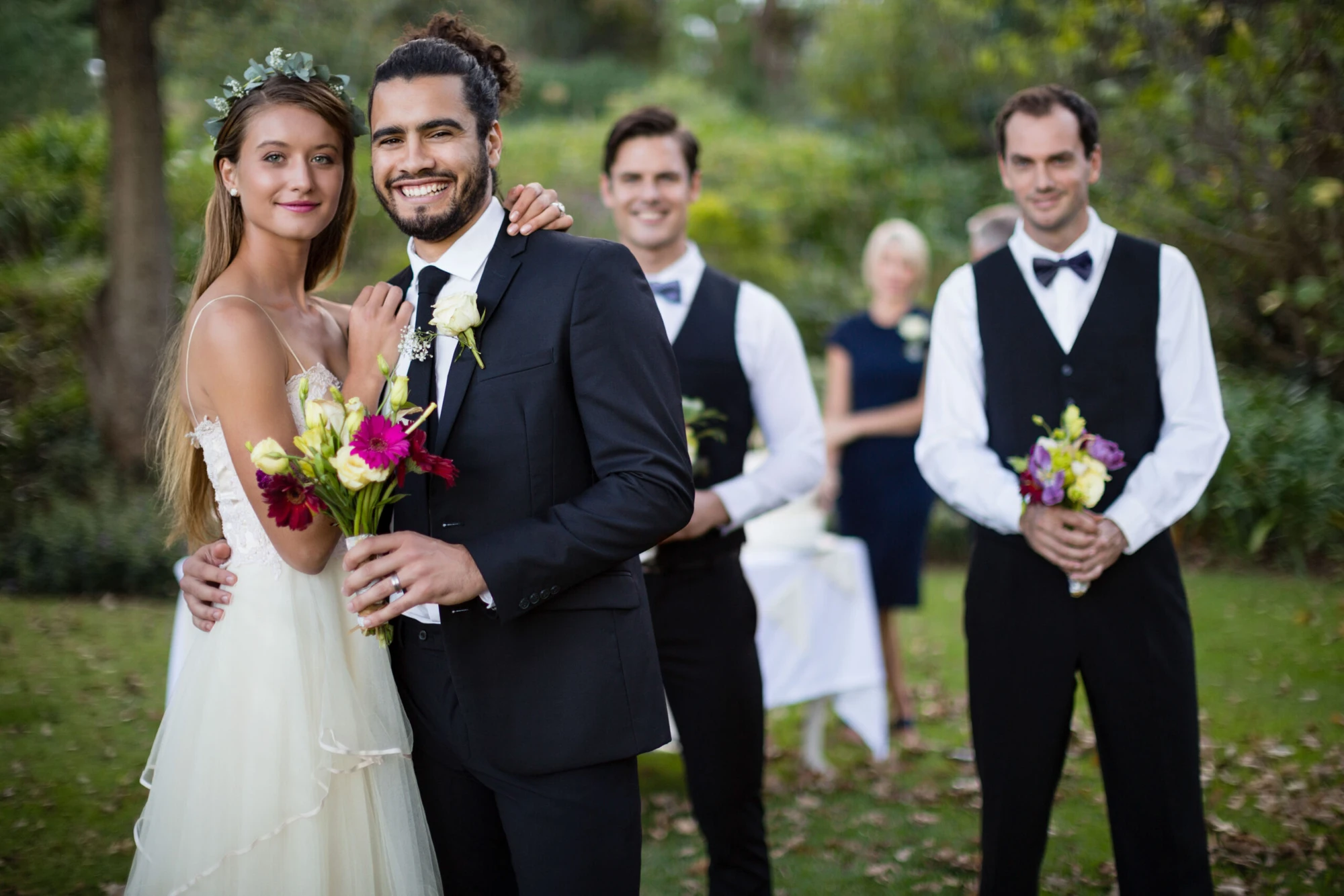 A wedding couple with their wedding party in a garden