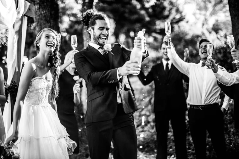 Newlyweds opening champagne outdoors