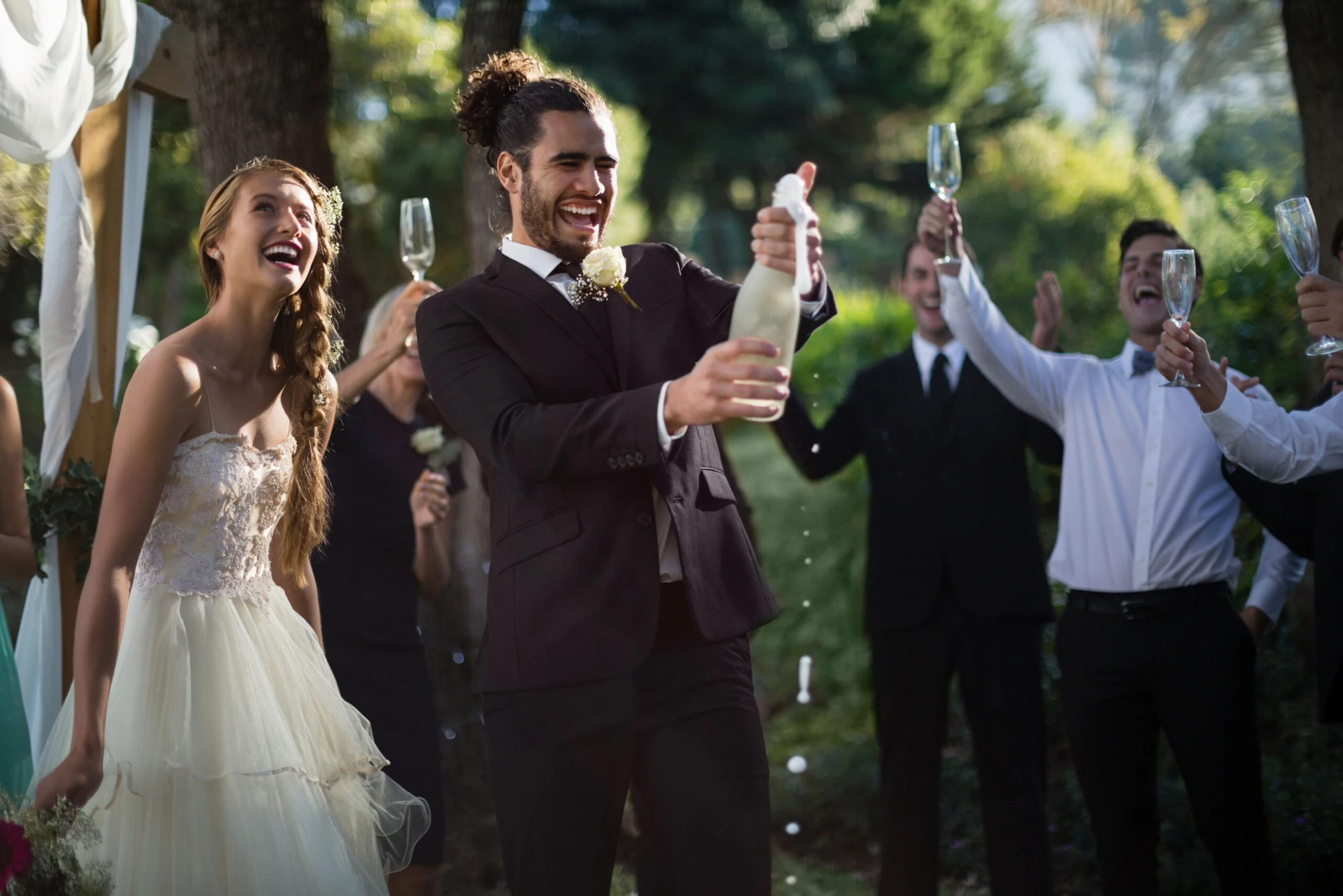 Newlyweds opening champagne outdoors