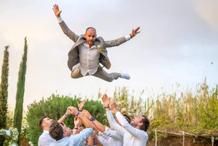 Groom tossed in the air by wedding guests