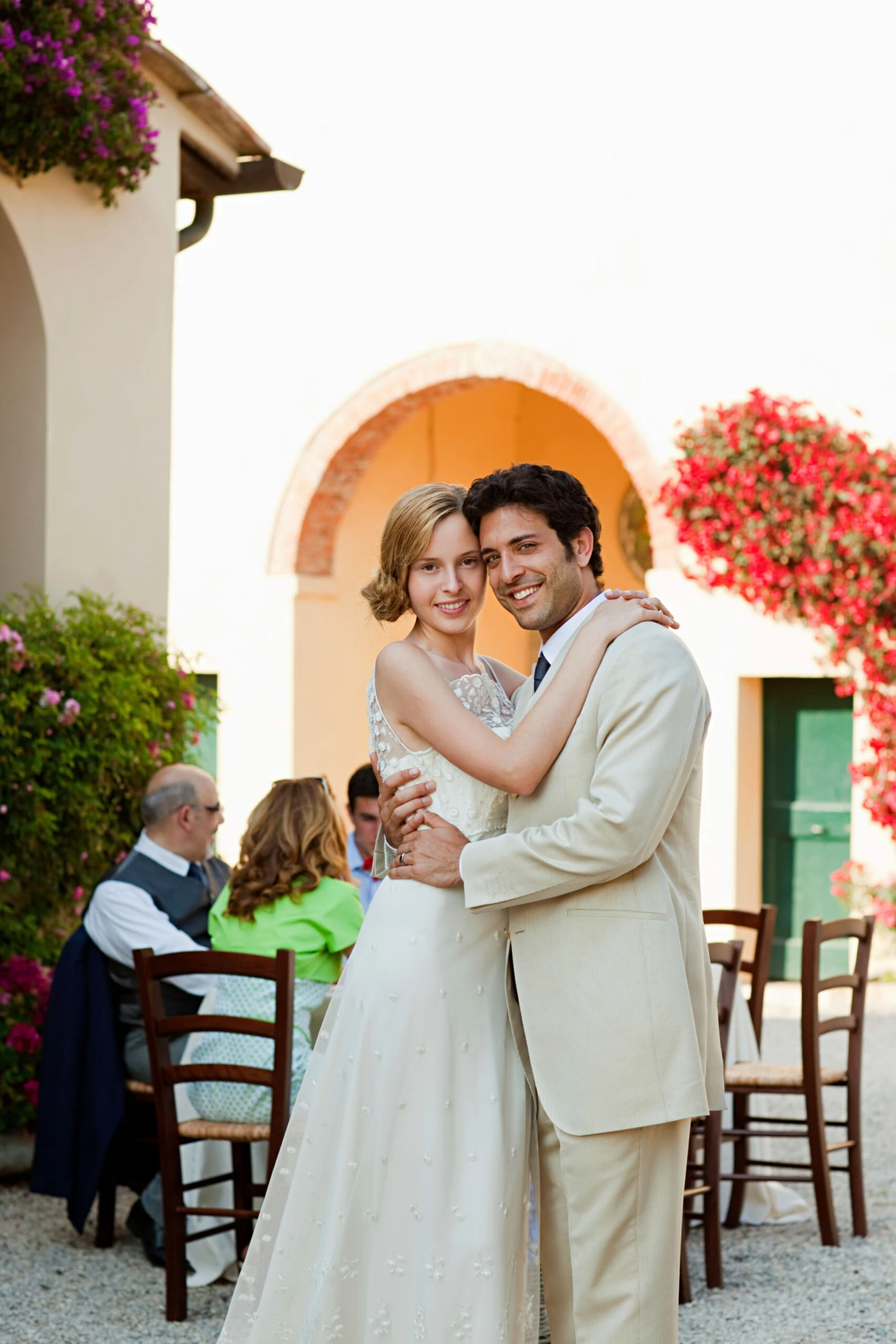 Newlyweds embracing in a flower-filled courtyard
