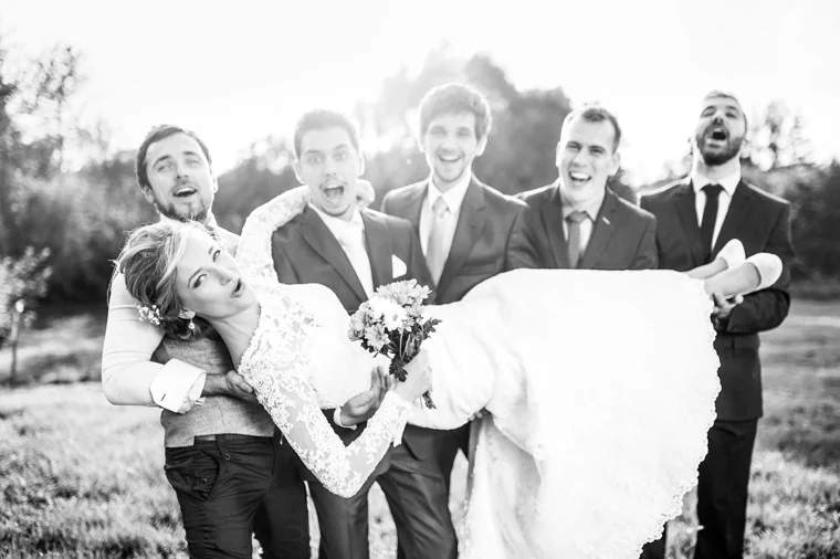 Wedding party carrying a laughing bride