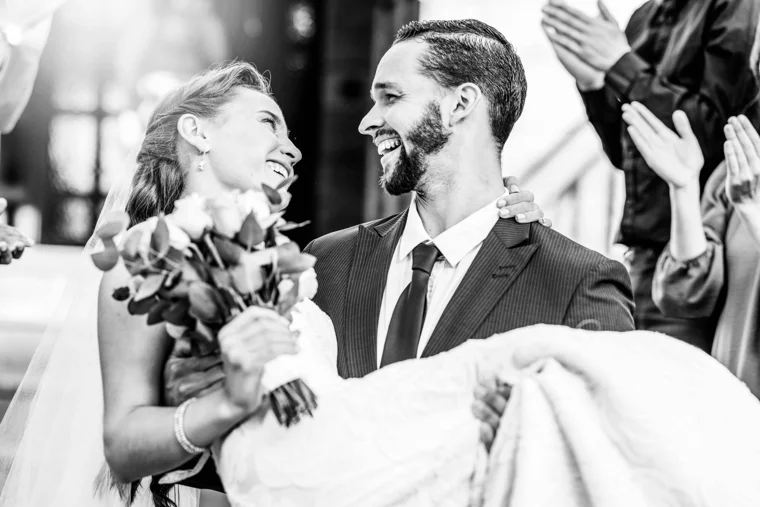 Groom holding the bride as they laugh