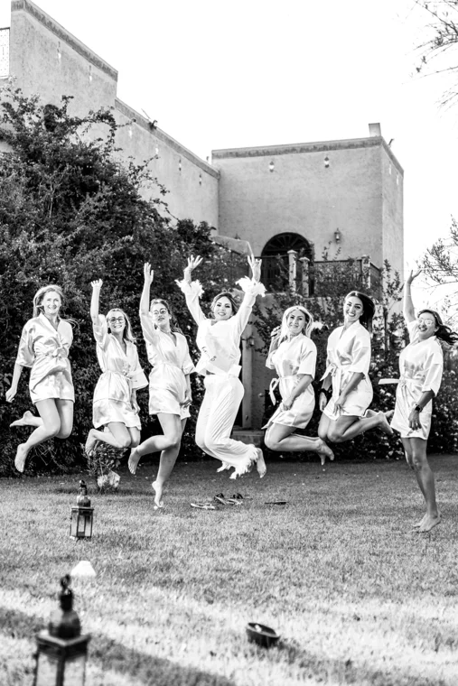 Wedding party jumping together in a garden